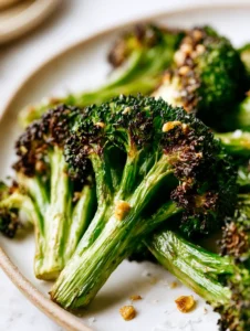 Extreme macro close up of a crispy garlic air fryer broccoli floret showing the fibrous stem and charred crown edges. (Air Fryer Broccoli)