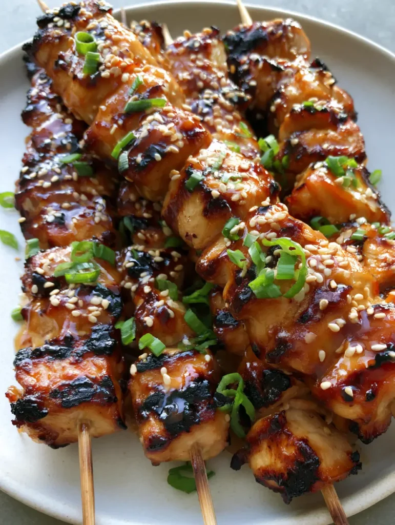 Succulent chicken breast cubes on wooden skewers with glistening honey garlic sauce and charred edges.