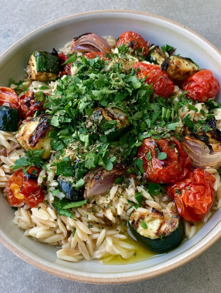Roasted Vegetable Orzo Salad with Lemon Vinaigrette and Charred Zucchini 1 A top-down view of the Roasted Vegetable Orzo Salad in a ceramic bowl, garnished with heavy flat-leaf parsley and dried herbs.