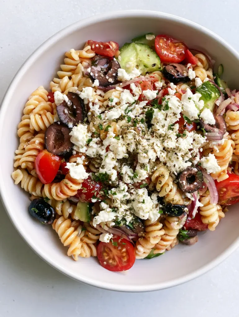 Greek Olive Pasta Salad: The Ultimate Zesty Mediterranean Recipe 2 Top-down view of Greek Olive Pasta Salad featuring rotini, cherry tomatoes, and cucumber in a shallow ceramic bowl.