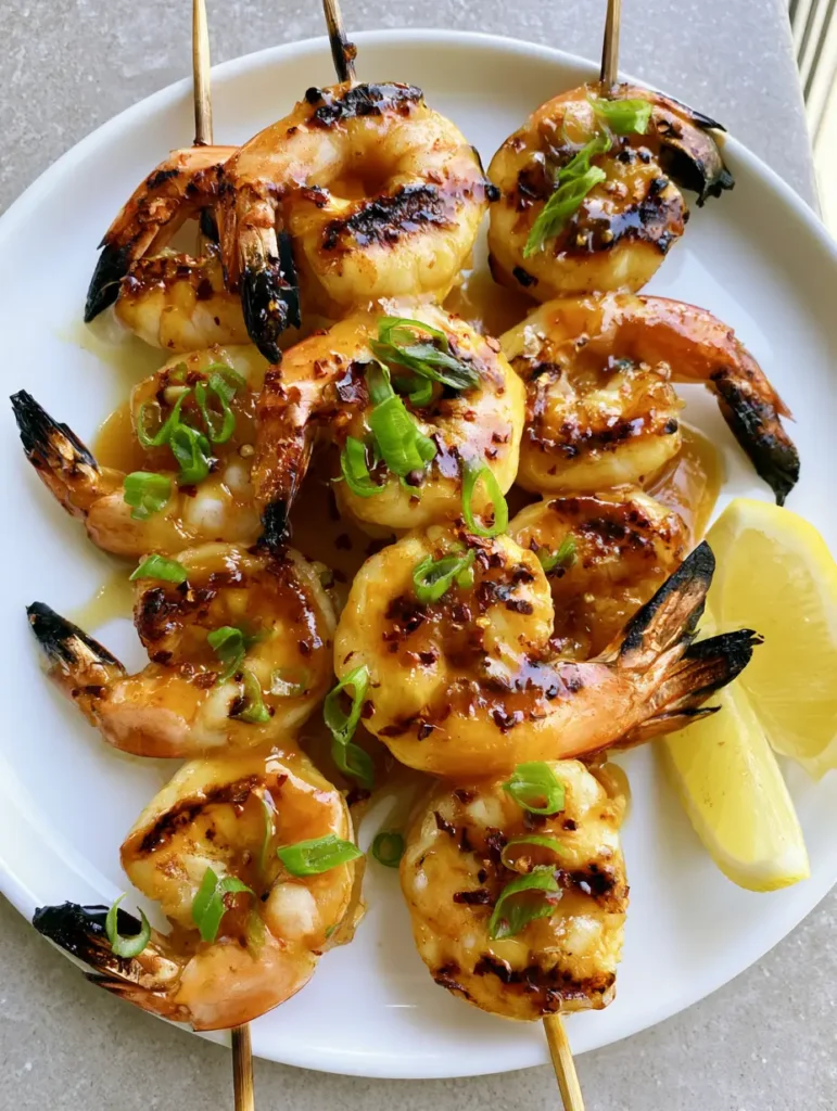 Honey Grilled Shrimp with Sticky Garlic and Charred Lemon 1 Close up of sticky Honey Grilled Shrimp showing the glossy glaze pooling in the curves of the seafood.