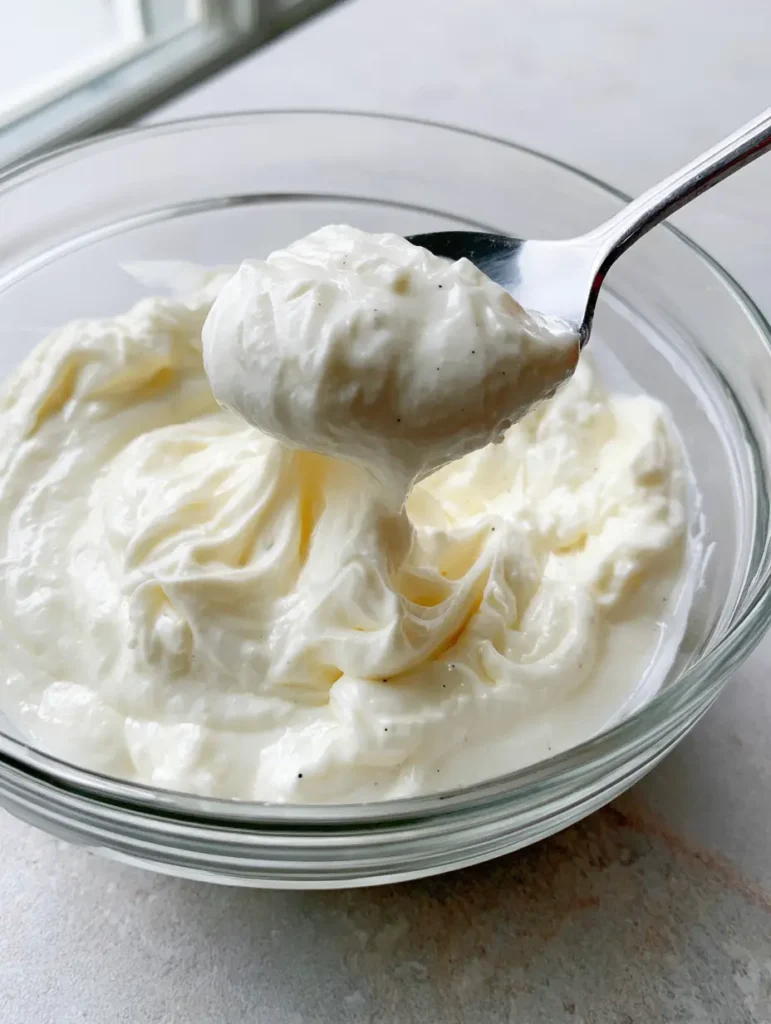 Powdered Sugar Frosting: The Ultimate 5-Minute Glossy Vanilla Glaze 1 A silver spoon lifting a creamy ribbon of Powdered Sugar Frosting, highlighting the pourable liquid state and shine.