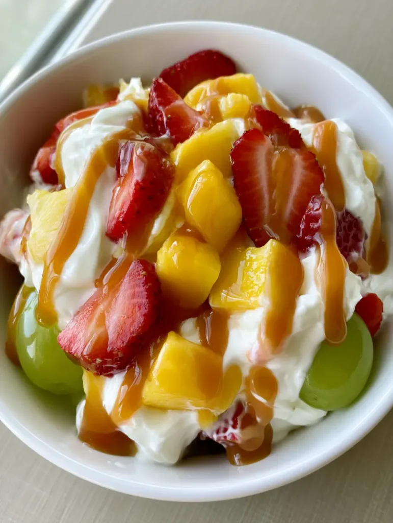 Cheesecake Fruit Salad with Glossy Caramel Drizzle 1 Detailed view of glossy strawberries and pineapple coated in cheesecake filling with translucent caramel sauce.