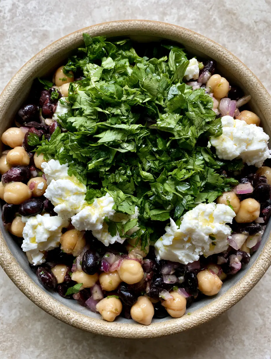 Chickpea and Black Bean Salad with Zesty Lime Vinaigrette 3 Overhead smartphone photo of Chickpea and Black Bean Salad featuring translucent red onions and glistening lime dressing in a textured bowl.