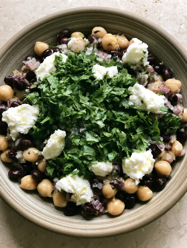 Chickpea and Black Bean Salad with Zesty Lime Vinaigrette 1 Close up of Chickpea and Black Bean Salad with a heavy scattering of bright green cilantro and large white feta chunks.