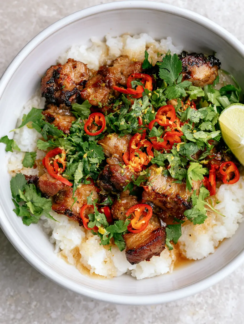 Ginger Lime Pork with Fluffy Coconut Rice and Glossy Zesty Glaze 3 Close-up of seared golden pork cubes coated in a glossy ginger lime glaze with red chili rounds and lime zest. (Ginger Lime Pork)
