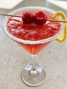 Close up of a Raspberry Lemon Drop Martini showing the light cocktail froth and granulated sugar rim.