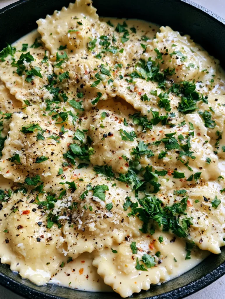 Close-up of tender crimped-edge ravioli submerged in a glossy Garlic Parmesan Ravioli Sauce with heavy herb garnishing.