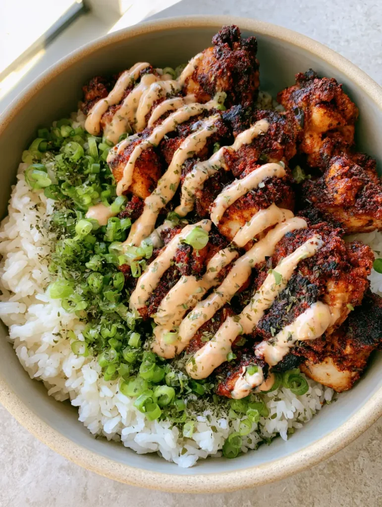 Crispy Cajun Chicken Rice Bowl with Creamy Spicy Mayo 2 Close-up of crispy fried chicken with Cajun spices and green onions in a white bowl.