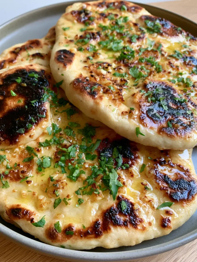 Garlic Naan Bread Recipe: Soft, Pillowy, and Skillet-Charred 1 Handheld photo showing the flexibility and glistening butter of the Garlic Naan Bread Recipe.