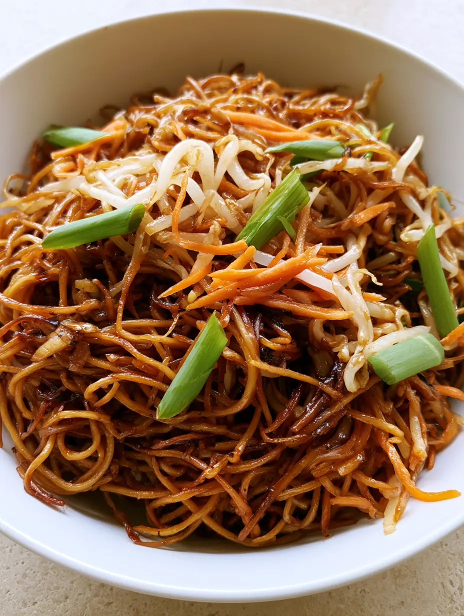 Smartphone photo of a Chow Mein Recipe in a white ceramic bowl showing dark soy glaze and scallions.
