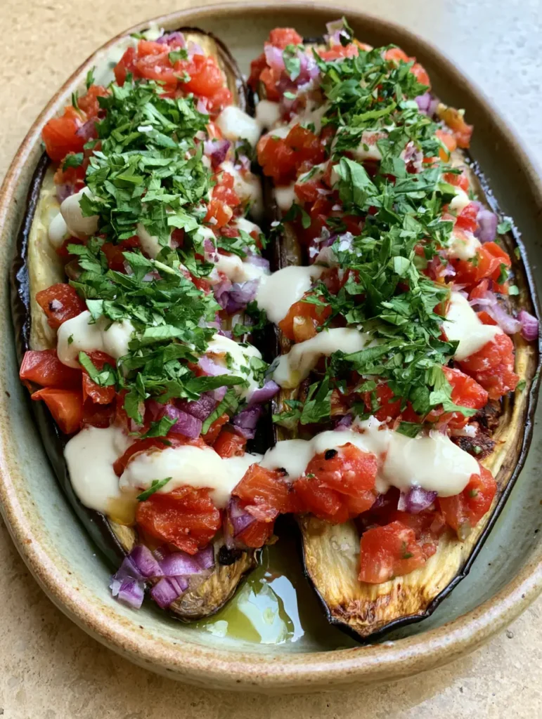Mediterranean Roasted Eggplant with Creamy Tahini and Fresh Garnish 1 Chunky tomato and onion topping with fresh parsley on top of Mediterranean Roasted Eggplant.