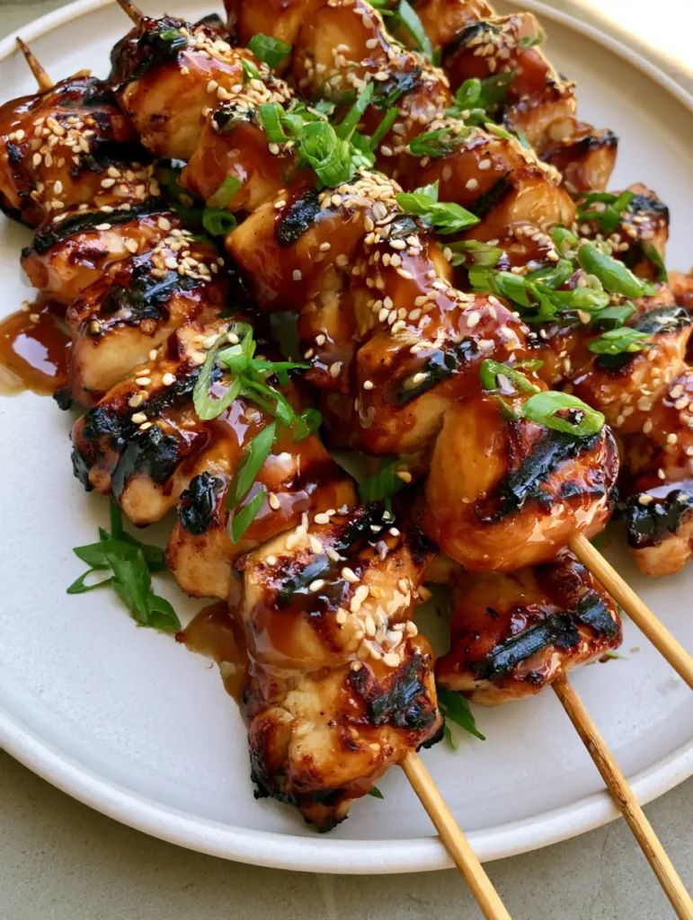 Top-down view of tightly packed Honey Garlic Chicken Skewers with caramelized grill marks and sesame seeds garnish.