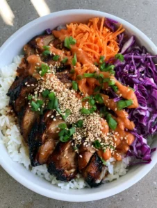 Close up of seared chicken breast with charred edges and glossy BBQ glaze. (Korean BBQ Chicken Bowls)