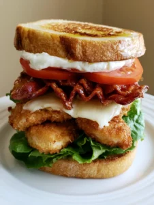 Close-up handheld photo of a Loaded Chicken Club Sandwich with grilled sourdough and melted white cheddar.