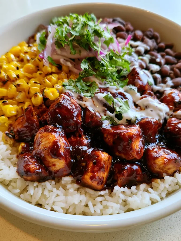 BBQ Chicken Rice Bowls: The Ultimate 20-Minute Weekday Meal 2 Close up handheld photo of BBQ Chicken Rice Bowls featuring caramelized chicken cubes and bright yellow corn.