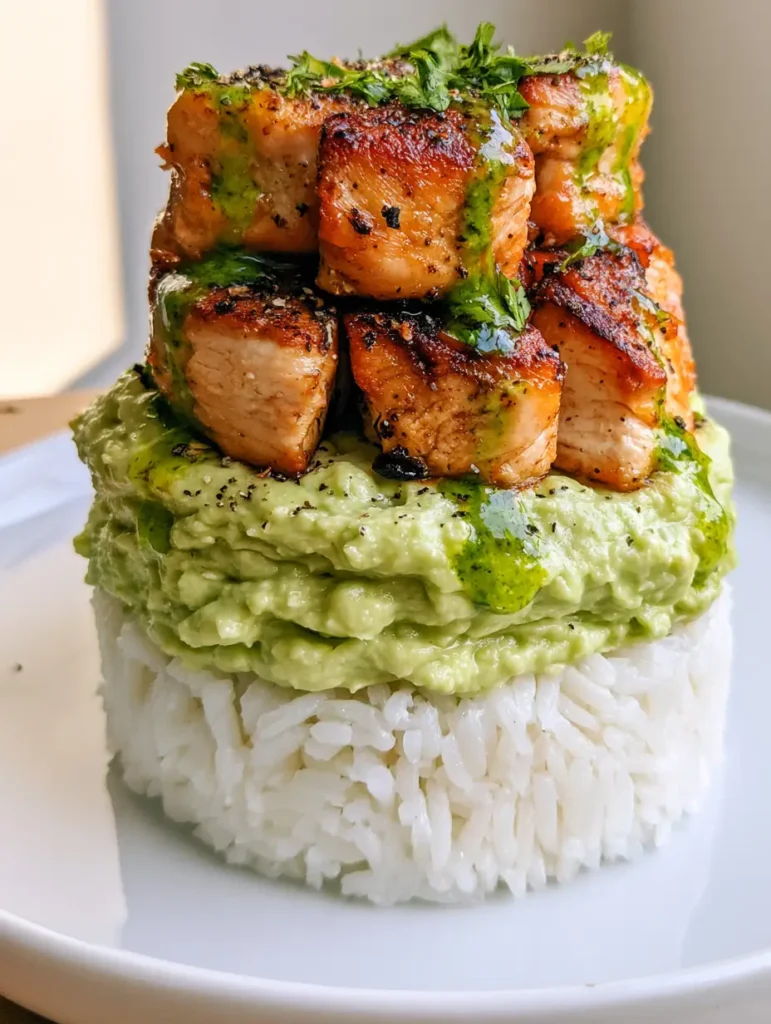 Honey Lime Chicken Avocado Stack with Fluffy Rice 2 Close up shot of the charred chicken cubes and cilantro lime sauce on a Honey Lime Chicken Avocado Stack.