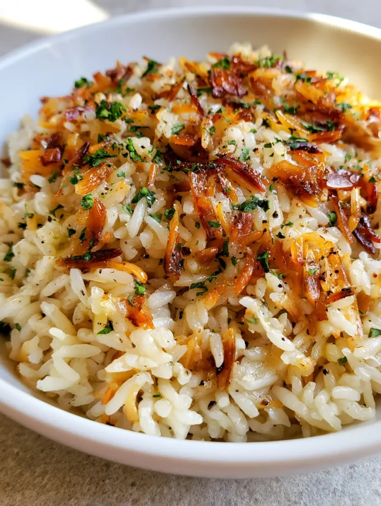 Close-up of toasted amber vermicelli noodles mixed with white long-grain rice in a white bowl.