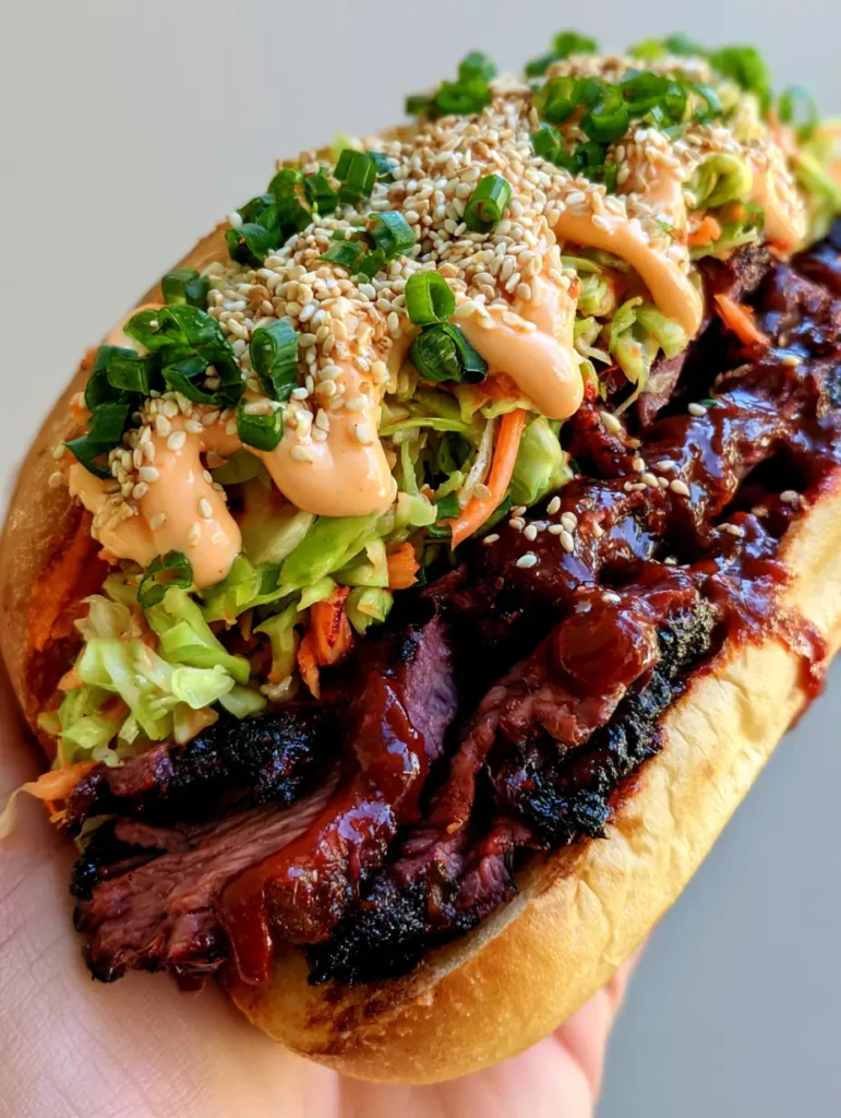 Top view of a Korean Steak Sandwich with vibrant cabbage slaw, sesame seeds, and green scallions.