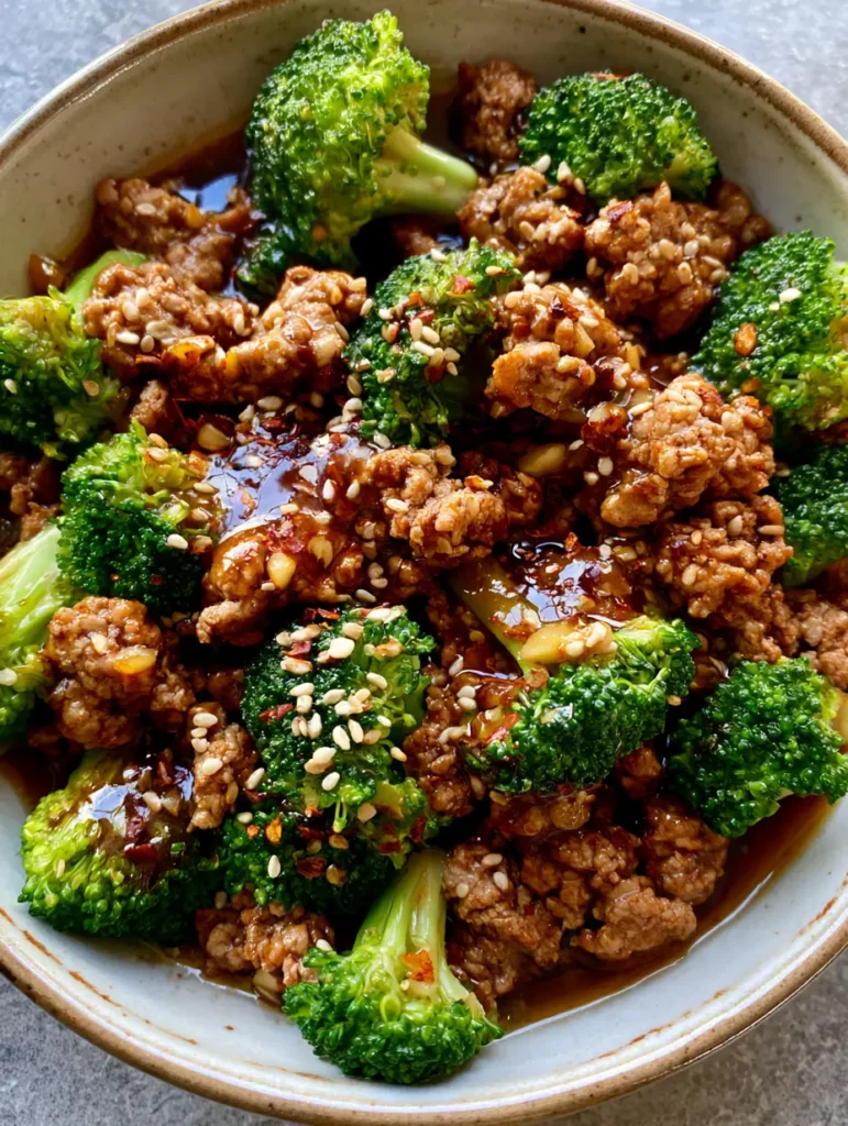 Ground Turkey Stir Fry with Garlic Broccoli and Glossy Soy Sauce 2 Top-down view of a Ground Turkey Stir Fry in a ceramic bowl with visible garlic bits and glossy sauce on a stone surface.